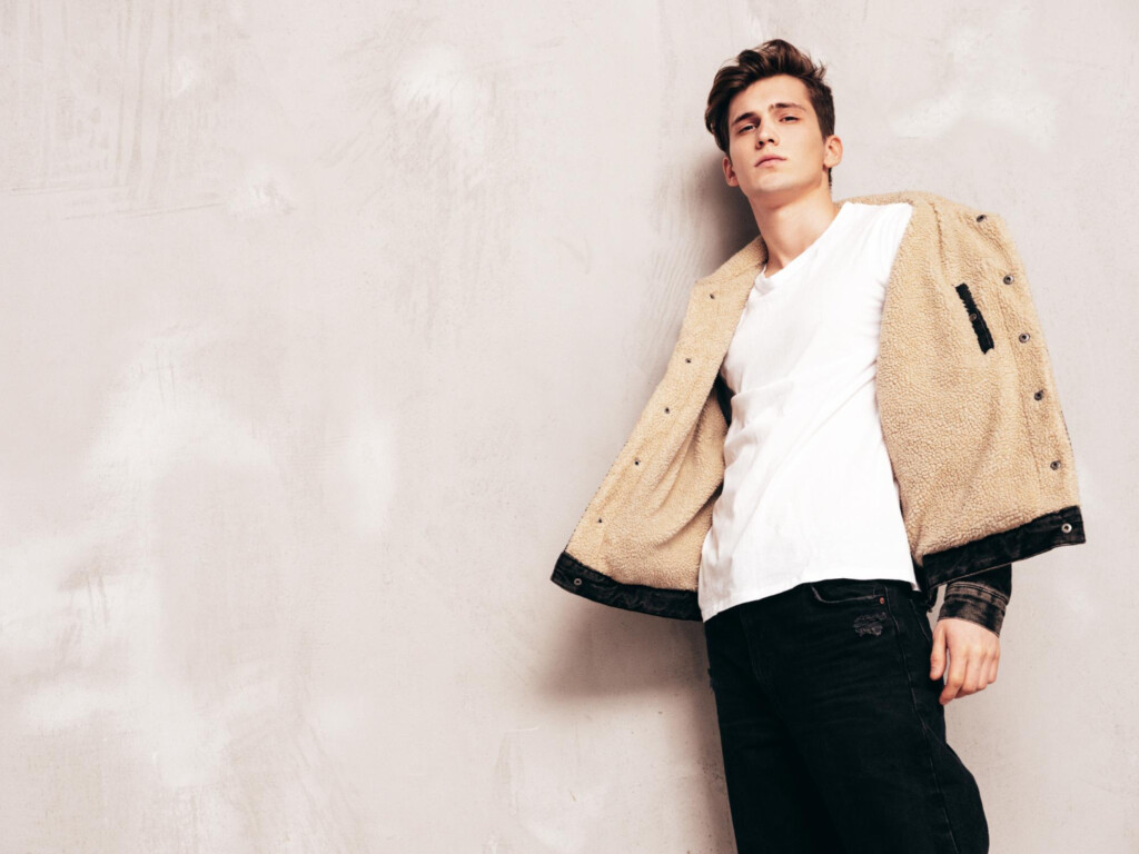 portrait-of-handsome-confident-stylish-hipster-lambersexual-modelman-dressed-in-black-jacket-and-jeans-fashion-male-posing-in-studio-near-grey-wall